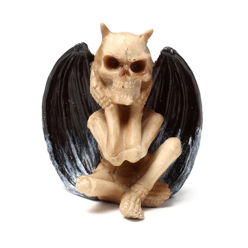 Bone-coloured winged skeleton figurine, portraying the 'Hear No Evil' demon ornament with black, textured wings, shown seated with its hands covering its ears on a white background.