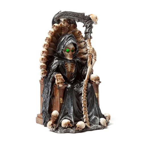 Front view of a decorative LED ornament depicting the Grim Reaper with glowing green eyes, seated on a throne made of skulls and holding a scythe.