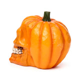 Side profile of an orange pumpkin skull ornament, featuring visible teeth and a green stem.
