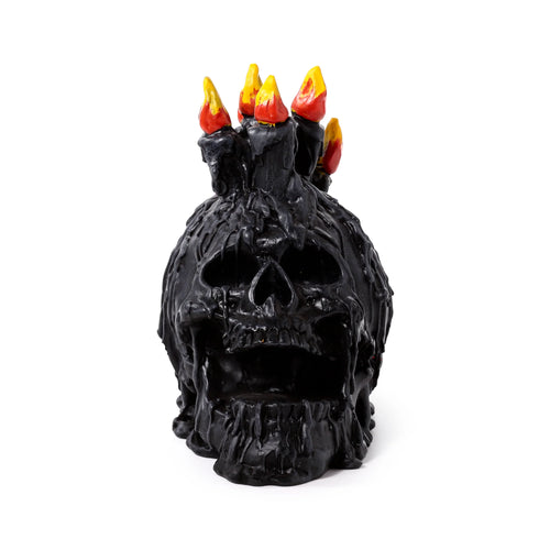 Front view of a decorative black screaming skull ornament with melted wax details and red and yellow candle flames on top.