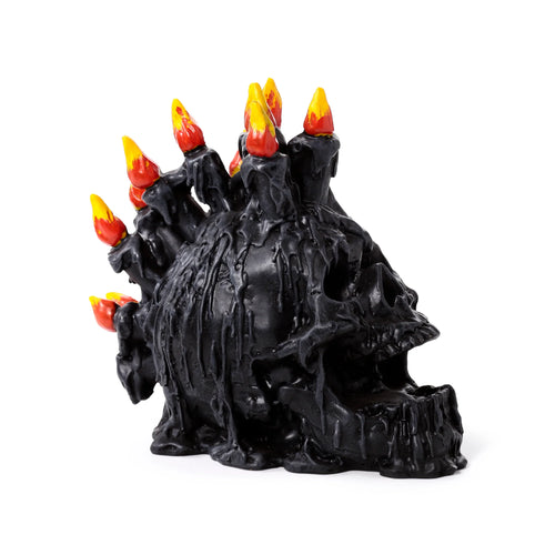 Angled view of a black screaming skull decorative ornament with black candles, red and yellow flame-effect tips, and melted wax detailing.
