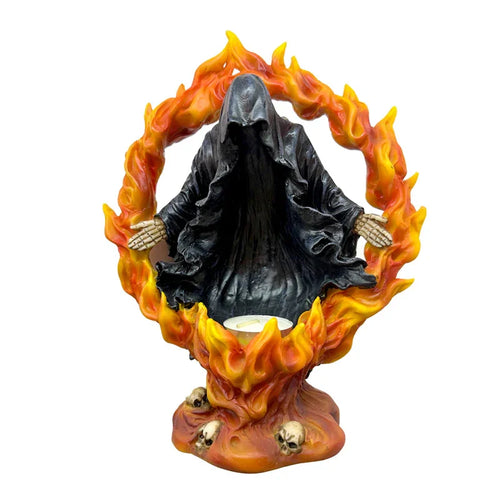 Front view of a black hooded Reaper of Death tea light holder, featuring skeletal hands and encircled by fiery orange flames. Small skulls adorn the base, with a white tea light visible.