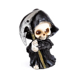 Front view of a decorative Grim Reaper skull figurine with a beige skull face and brown eyes, wearing a black hooded robe and holding a silver-bladed scythe.