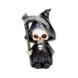 Front view of a decorative mini skull reaper ornament, wearing a black hooded cloak, holding a silver scythe, and featuring a small skull emblem on its chest.