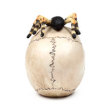 Rear view of a decorative ornament depicting a light-coloured skull with prominent dark sutures on top, a black and beige striped spider resting on its crown.