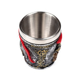 Decorative Roman Soldier shot glass with a metallic interior and an aged dark grey exterior featuring gold ornate patterns and a prominent red plume detail, viewed from an overhead angle.