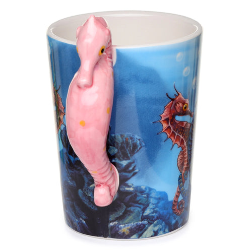 Angled view of a ceramic mug with a pink seahorse-shaped handle, featuring a blue underwater design and other seahorses.