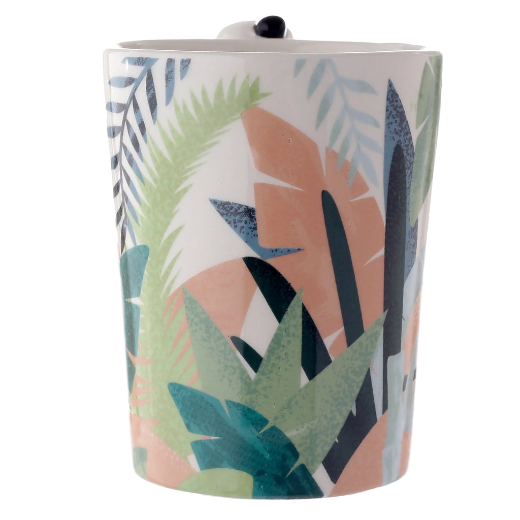 Angled view of a white ceramic mug featuring a vibrant abstract tropical foliage pattern in shades of green, blue, and peach; a small black detail of the shaped handle is visible at the top rim.