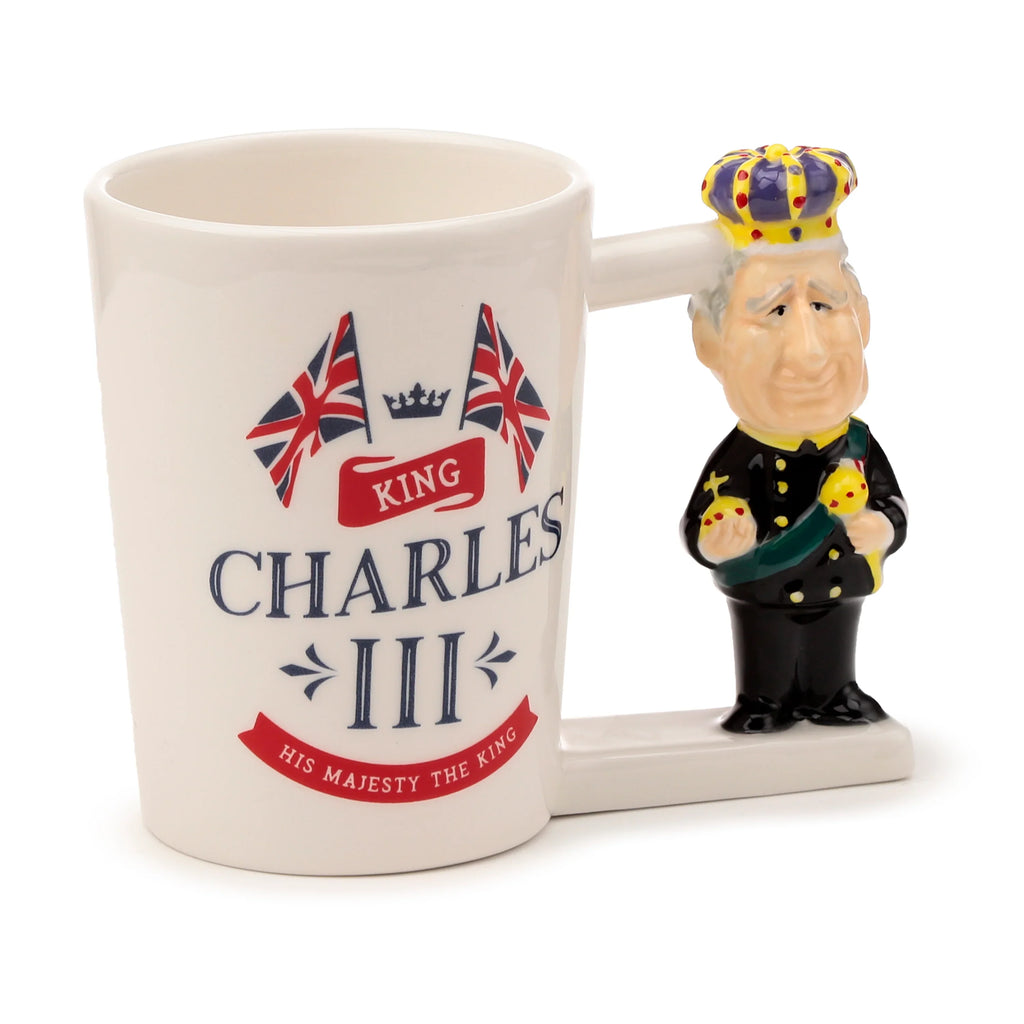 Angled view of a white ceramic novelty mug with a decorative King Charles III shaped handle. The mug features Union Jack flags and 'King Charles III His Majesty The King' text on its side.