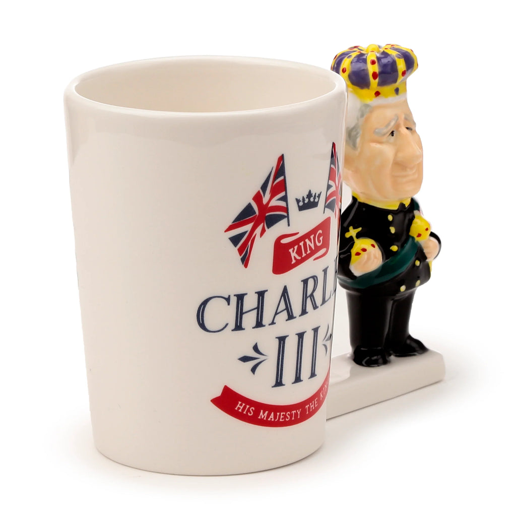 Angled view of a white novelty ceramic mug with a King Charles III shaped handle, depicting Union Jack flags and 'King Charles III' text.
