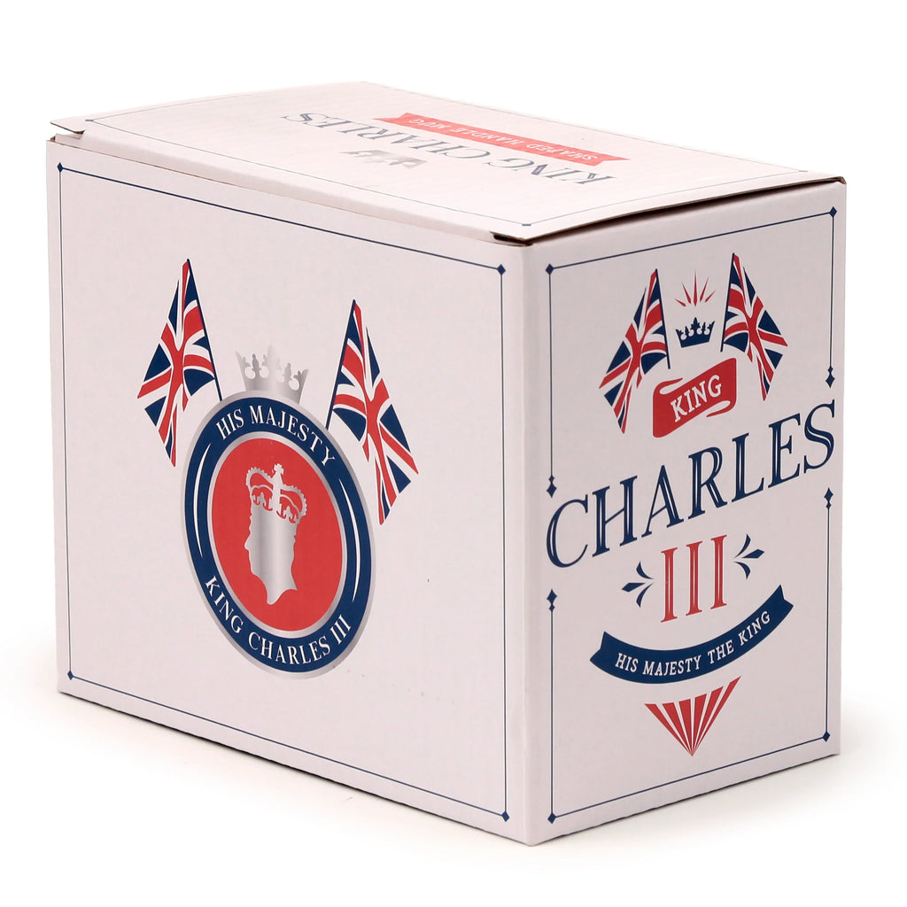 Angled view of a white cardboard novelty mug packaging box, adorned with King Charles III themed graphics. The visible top, front, and side panels feature Union Jack flags, a royal crown, the text 'King Charles III', and a silhouette of the King.