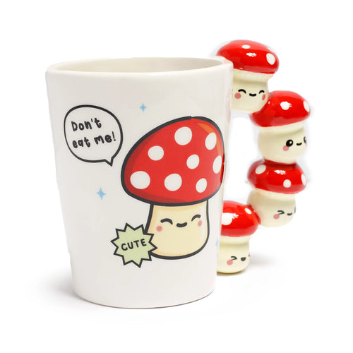 Angled view of a white ceramic mug with a red and white toadstool graphic and 'Don't eat me!' text, featuring a shaped handle composed of stacked, smiling mushroom figures.