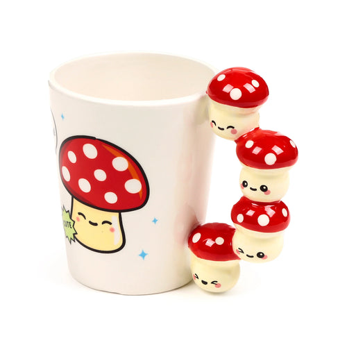 Angled view of a white ceramic mug, featuring a cute red and white mushroom graphic on the side. The handle is shaped like a stack of four cute red toadstool figures with smiling faces.