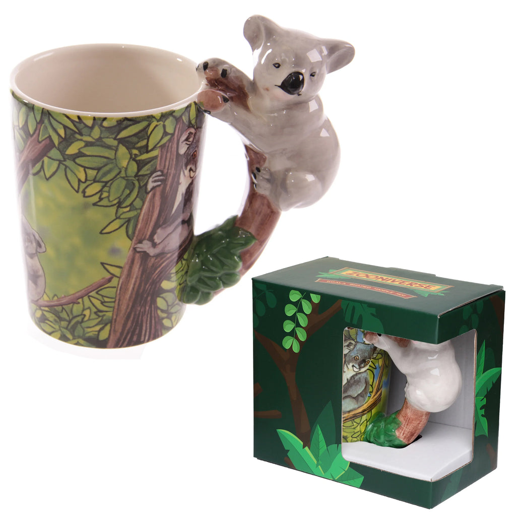Angled view of a ceramic novelty jungle mug featuring a grey koala shaped handle, depicting the koala climbing a tree. The mug's body displays a vibrant green jungle scene with trees and koalas, presented alongside its dark green gift box with a clear display window.