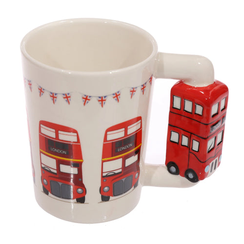 Angled view of a cream ceramic mug with a red double-decker London bus shaped handle, featuring matching bus illustrations and Union Jack bunting print on its side.