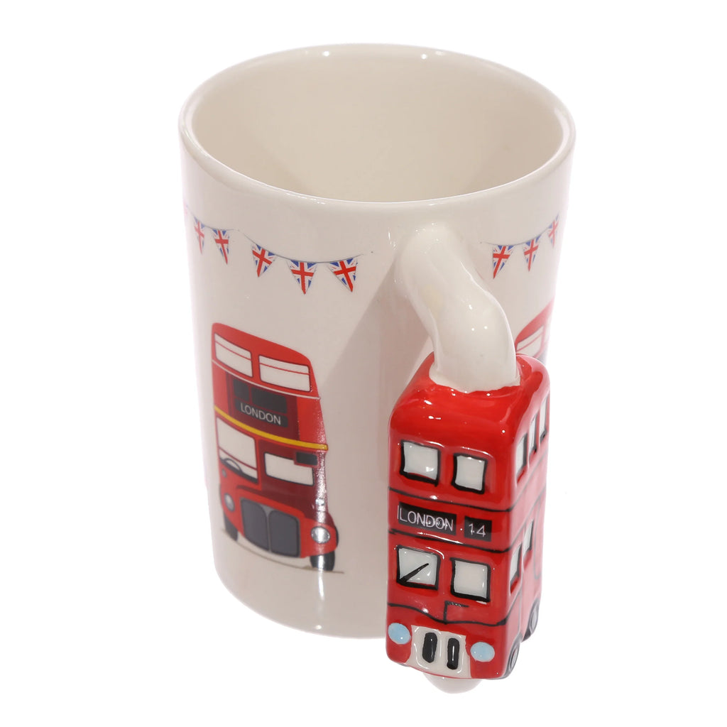 Angled view of a white ceramic mug, prominently displaying its red Routemaster London bus shaped handle and a matching London bus illustration on its side, detailed with Union Jack bunting.