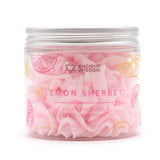 Front view of a clear jar of pink whipped soap, showing its fluffy, piped texture inside. It has a silver-coloured ridged lid. The label depicts pink and yellow lemon slices, and text reads 'WHIPPED LEMON SHERBET PINK LEMONADE SCENTED WHIPPED SOAP 120g | 4.23 OZ'.