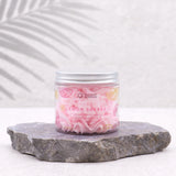 Front view of a clear jar of pink whipped soap, showing the 'Whipped Lemon Sherbet' and 'Pink Lemonade Scented Whipped Soap' label with citrus fruit designs, a silver lid, resting on a dark grey rock.