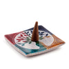 Angled view of a colourful soapstone incense burner dish with a carved Tree of Life design and a brown incense cone.