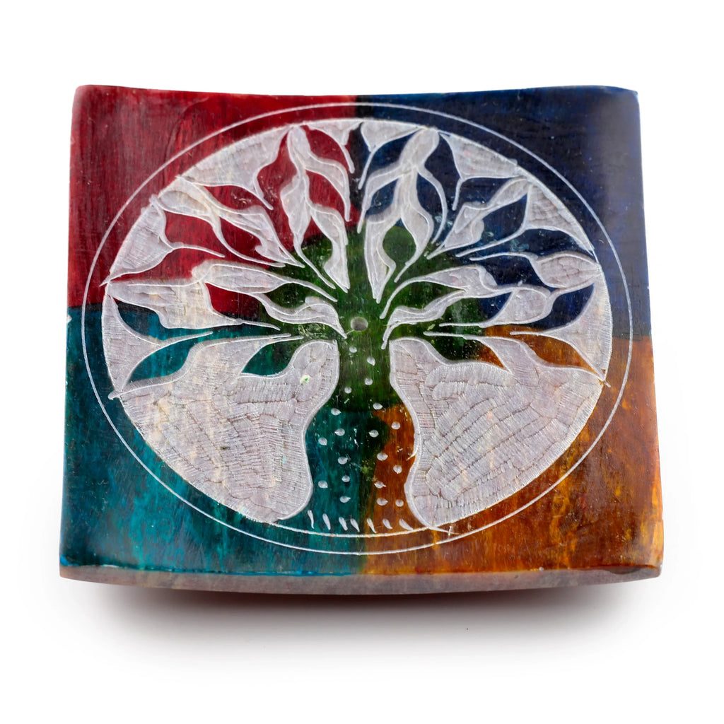 Angled overhead view of a vibrant, multi-coloured soapstone incense burner dish, featuring a carved white Tree of Life design and a small central hole for incense.