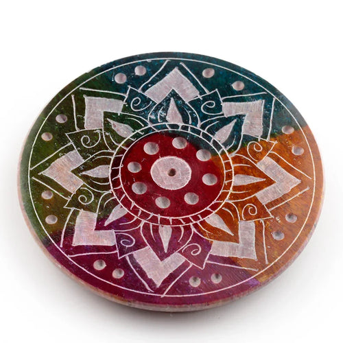 Overhead view of a circular soapstone incense burner dish, showcasing a vibrant multi-coloured, carved sunburst design with multiple holes for incense.