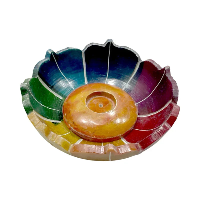 Angled top view of a carved soapstone chakra lotus incense burner dish, featuring colourful petals in green, blue, purple, red, and yellow, with a central brown incense holder.