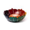 Angled view of a carved soapstone lotus incense burner dish, featuring multi-coloured petals in shades of red, orange, yellow, green, and deep blue with white accents, and a central holder with multiple holes.