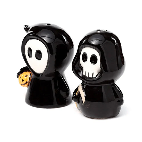 Angled view of a black and white ceramic salt and pepper set featuring a hooded Ghost Boy holding a pumpkin and a hooded Skull Boy holding a scythe.