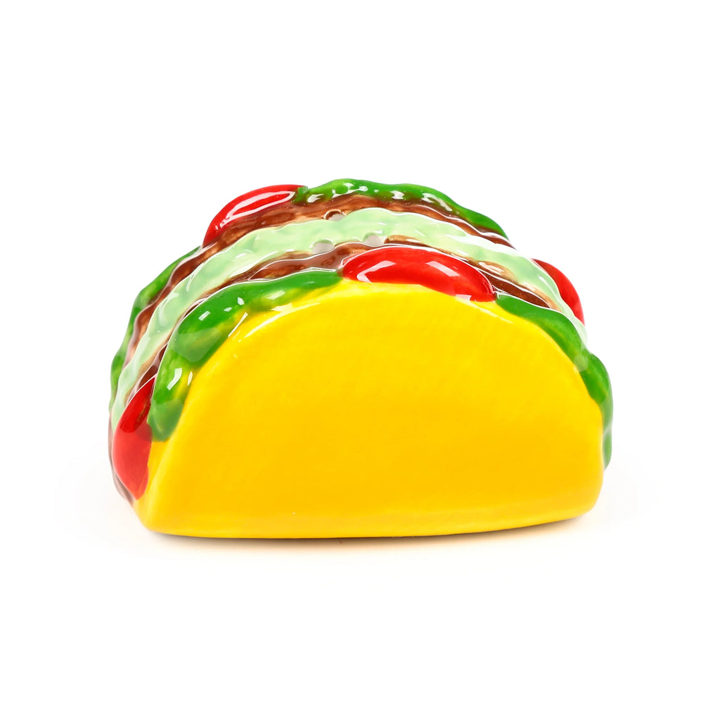 Angled view of a ceramic taco shaker, with a bright yellow shell and glossy green, brown, and red layered toppings.