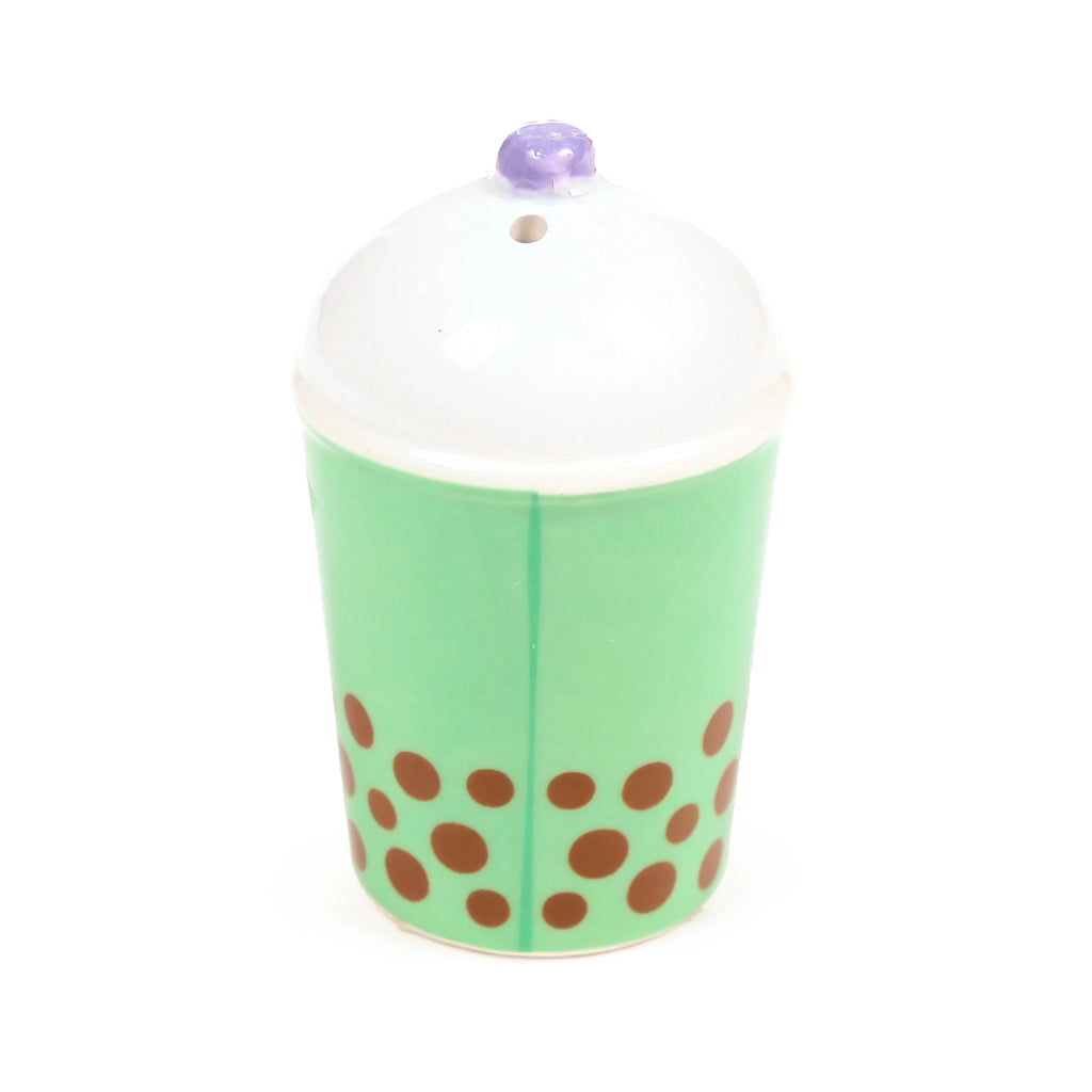 Ceramic salt or pepper shaker, shaped like a light green bubble tea cup, adorned with brown boba dots, a white foam top, and a small purple straw-like detail.
