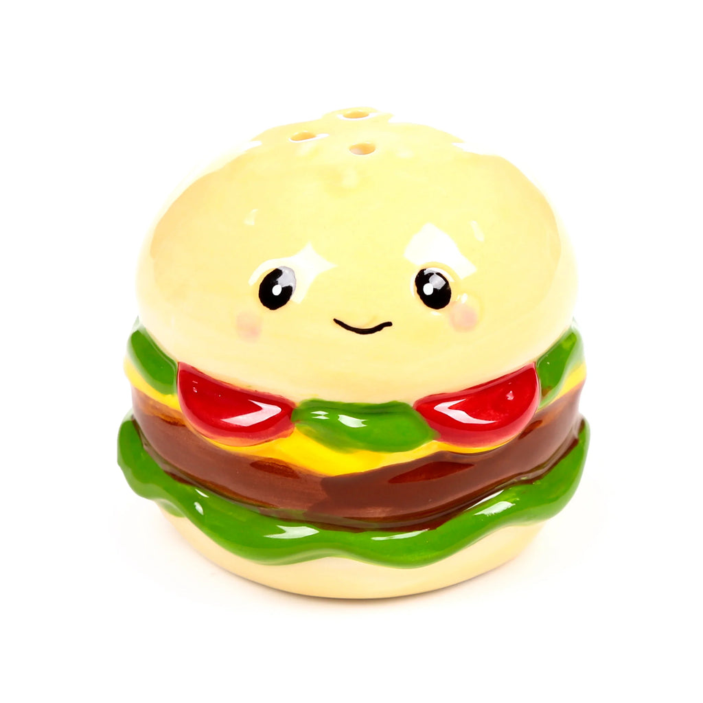 Front view of a glossy ceramic burger shaker, depicting a cartoon-style burger with cream buns, red ketchup, green lettuce, brown patty, and yellow cheese layers. It features a smiling face with black eyes and rosy cheeks, and three holes on the top bun.