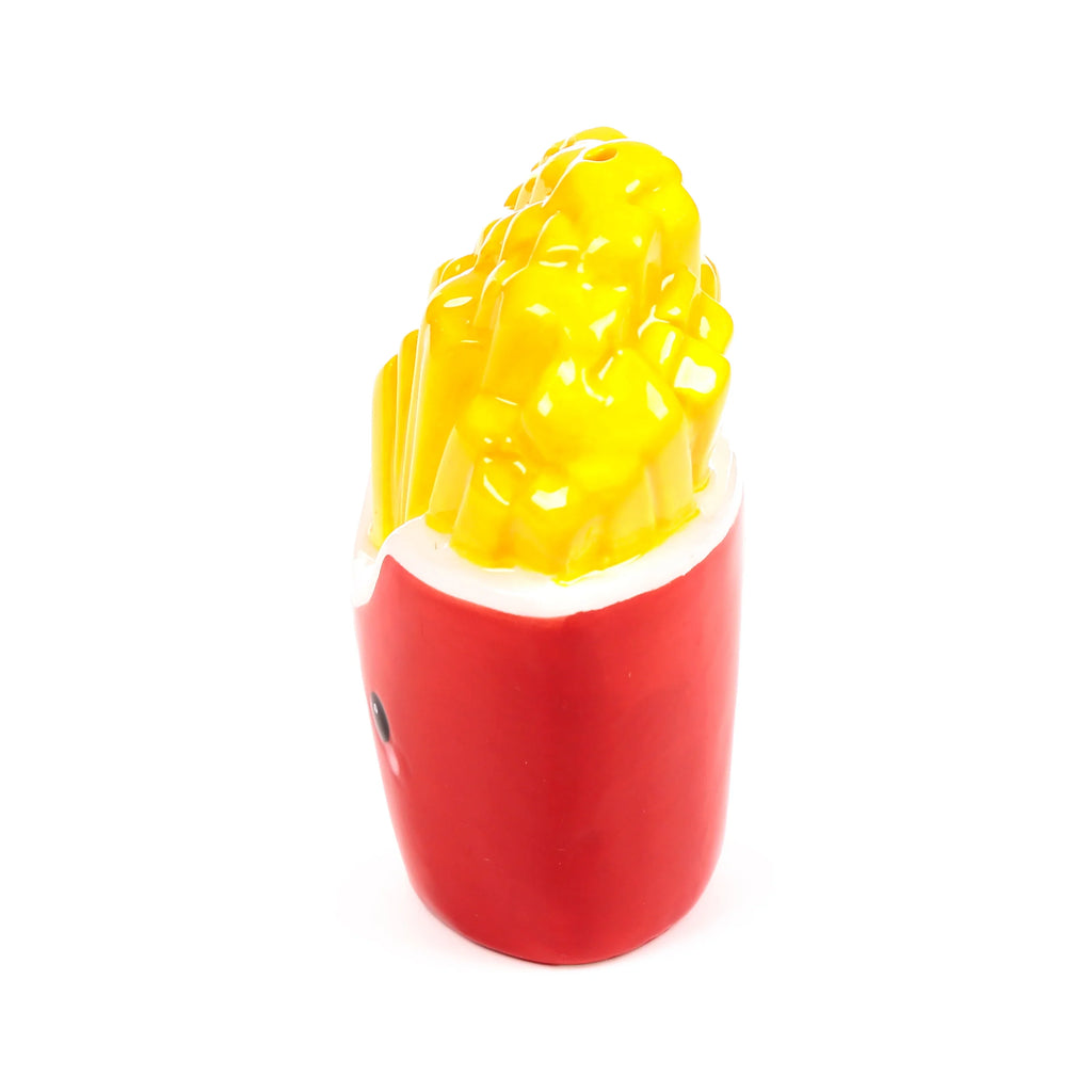 Angled view of a ceramic fries salt or pepper shaker, depicting textured yellow chips in a glossy red carton with a white rim and a small character eye on the side.