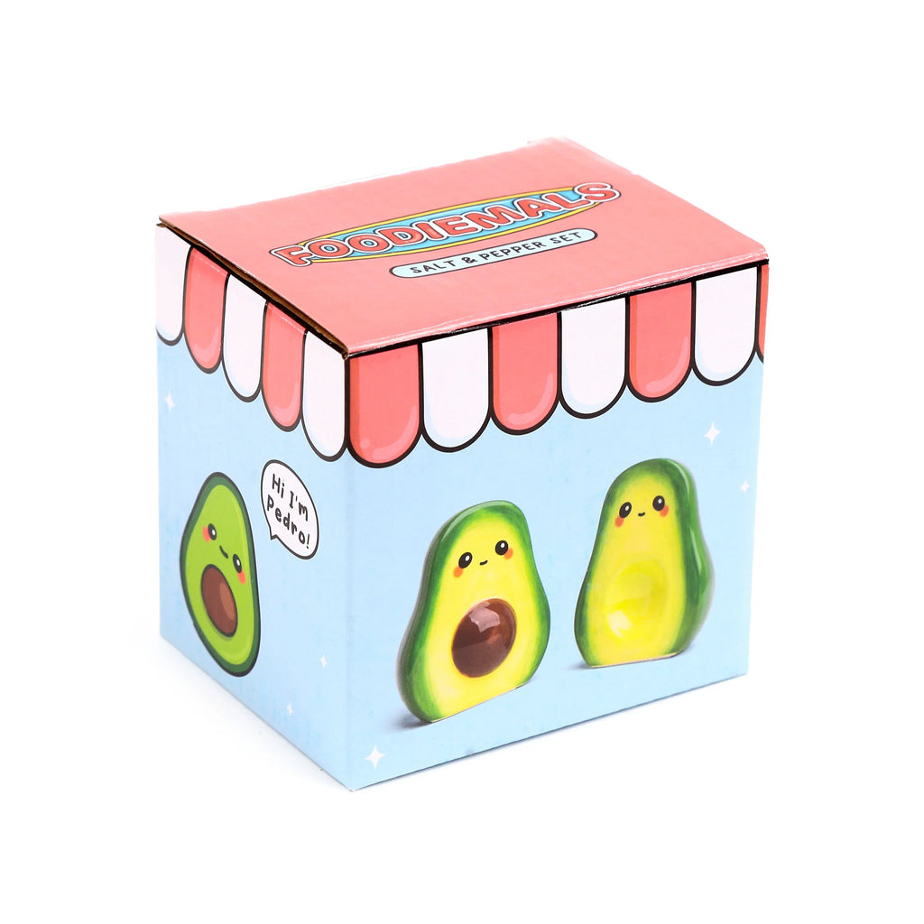 Angled view of the 'Foodiemals' ceramic avocado salt and pepper set packaging. The light blue box features cartoon avocado illustrations, one with 'Hi I'm Pedro!' and a pink awning-style lid.