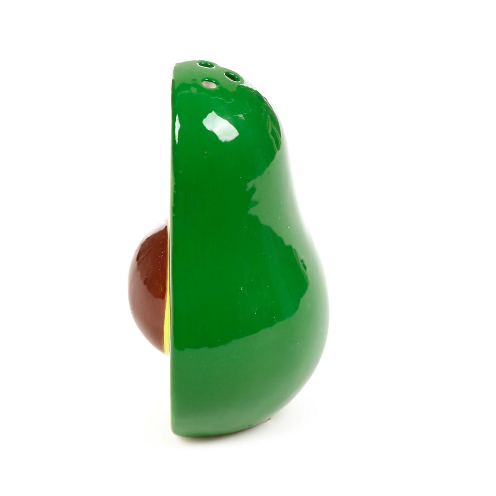 Side view of a glossy green ceramic avocado shaker, featuring a prominent brown pit and three dispensing holes on its top.