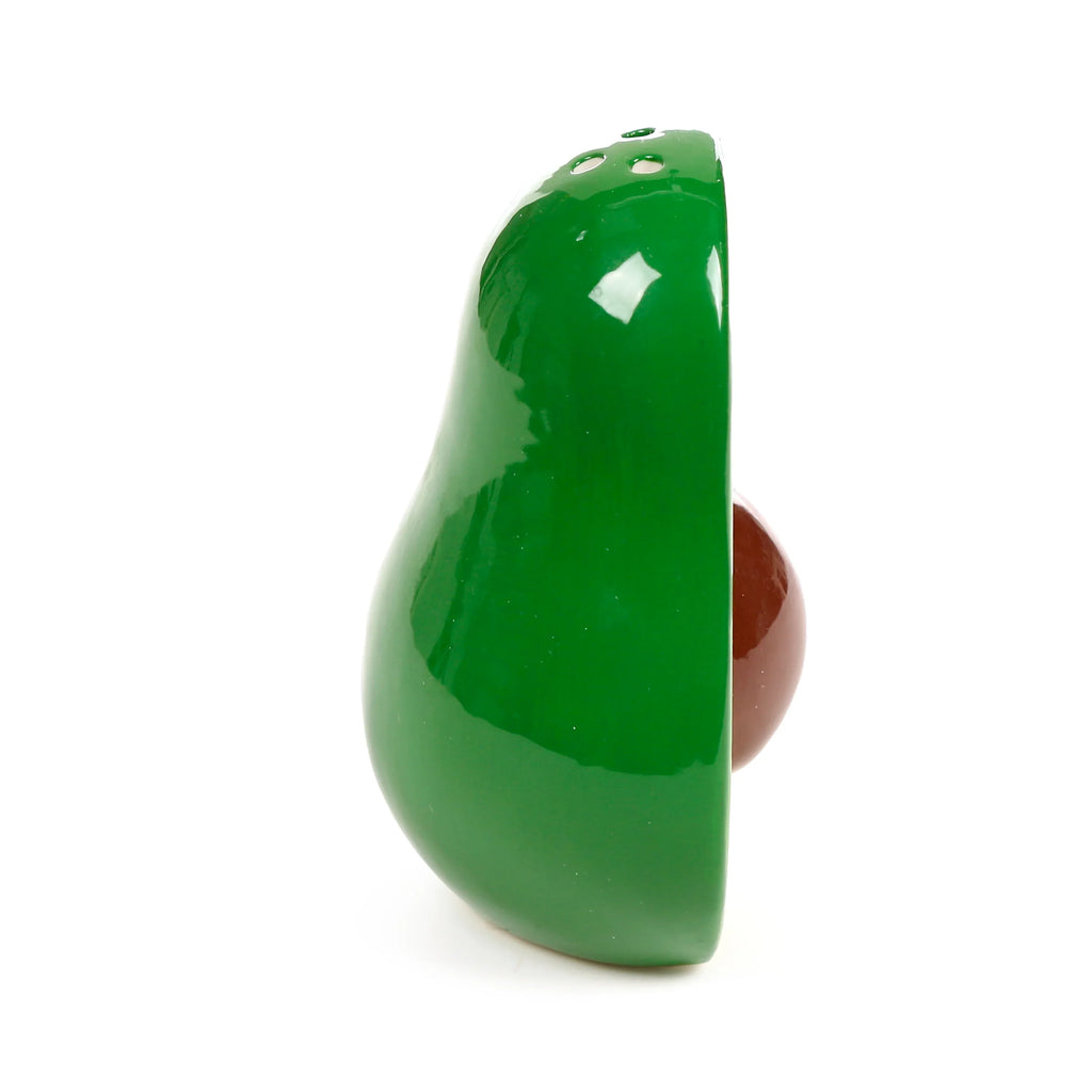 Profile view of a glossy green ceramic avocado shaker with a brown stone, from a salt and pepper set.