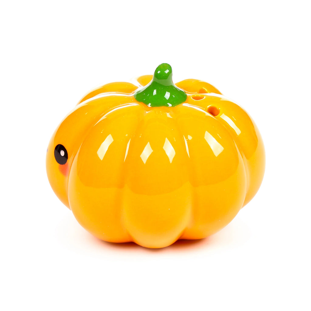 Angled view of a glossy orange ceramic pumpkin shaker, featuring a green stem, a black eye with a subtle reddish blush, and shaker holes on top.