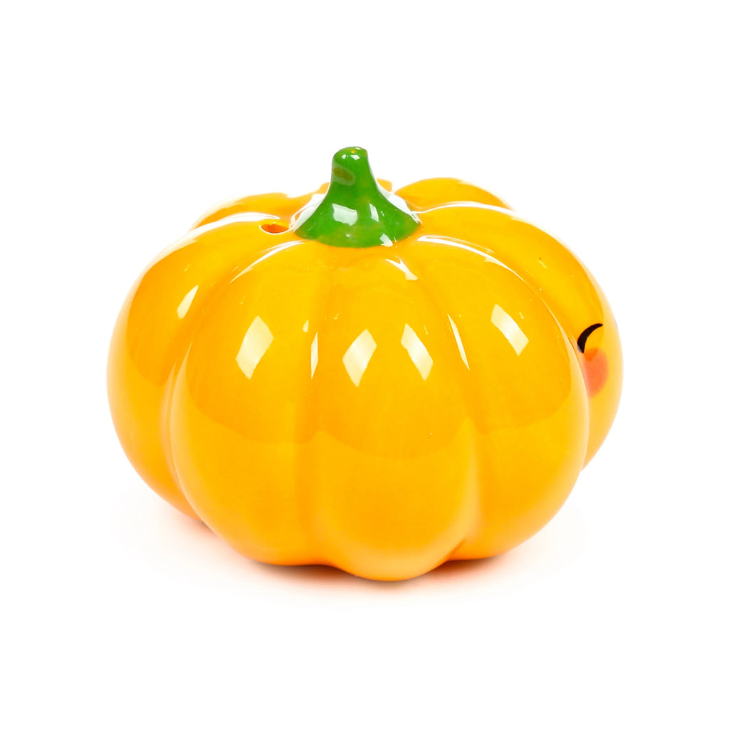 Angled view of a glossy orange ceramic pumpkin salt or pepper shaker with a green stem and subtle smiling face, on a white background.