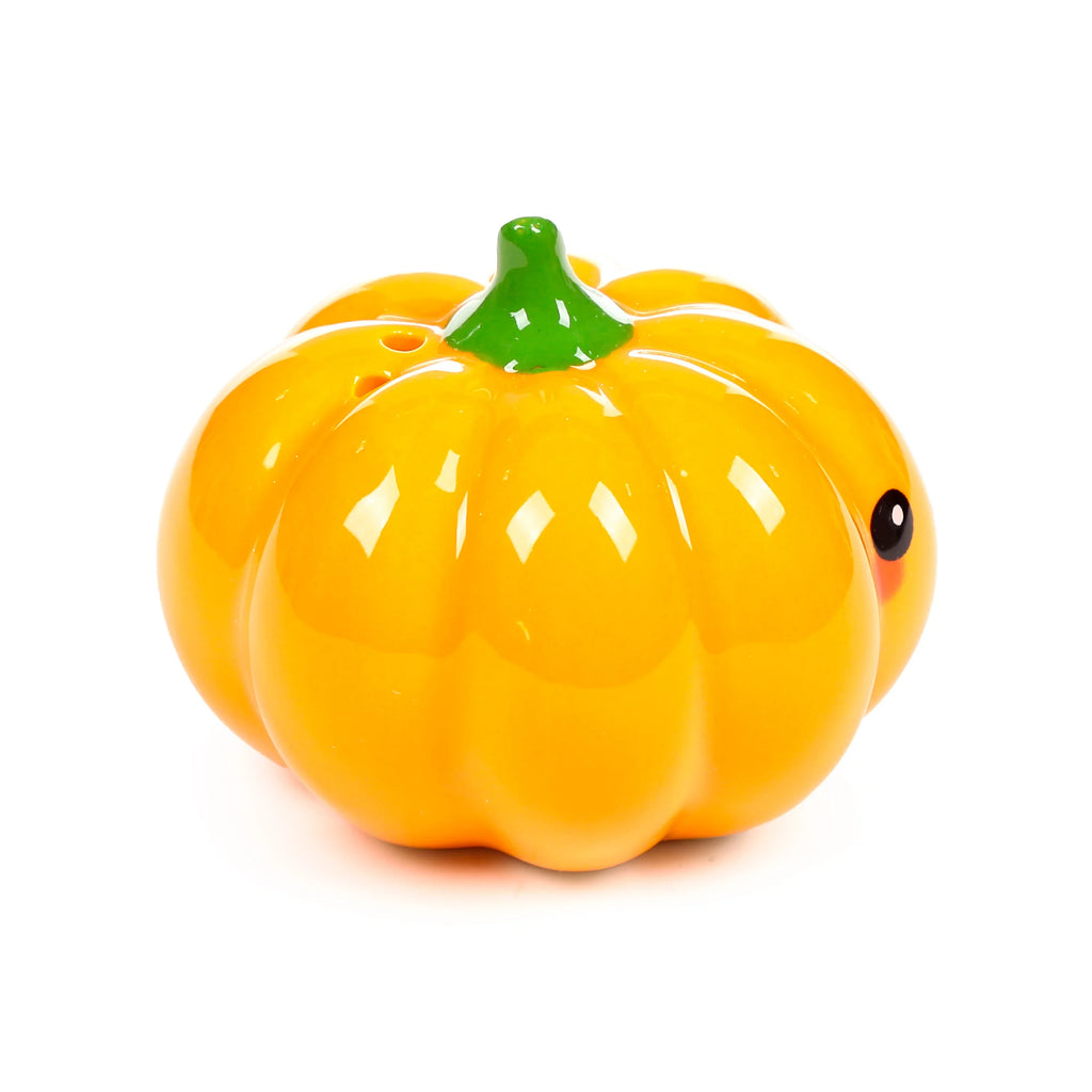 Angled view of a glossy orange ceramic pumpkin shaker with a green stem, dispensing holes, and a single black eye, displayed on a white background.