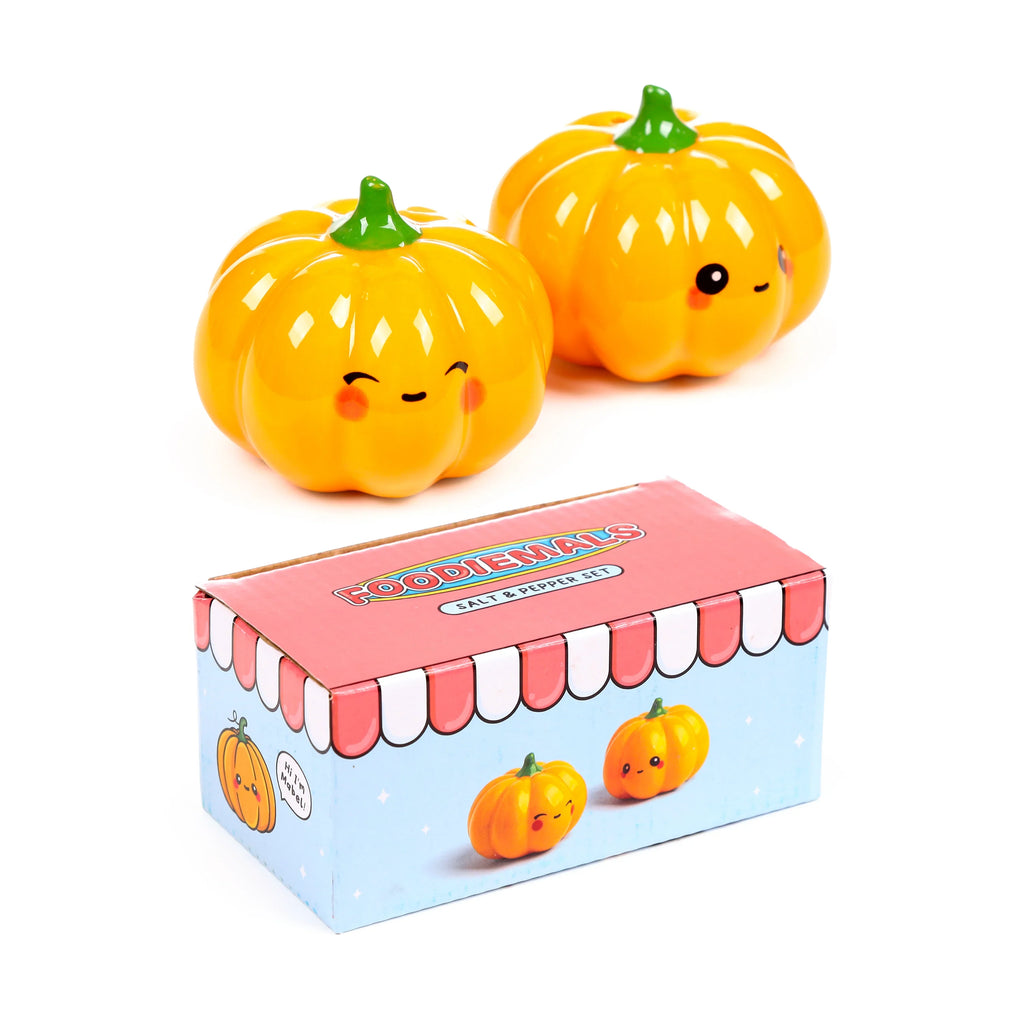 Angled view of a Ceramic Salt & Pepper Set, featuring two glossy orange pumpkin Foodiemals shakers with cute faces and green stems, positioned behind their decorative packaging box.