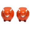 Front view of two ceramic orange Highland coo cow salt and pepper shakers with white horns, black eyes, and white muzzles on a white background.