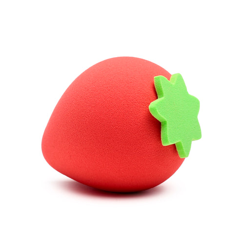 Red strawberry-shaped beauty blender sponge with a green calyx, displaying its textured surface, on a white background.