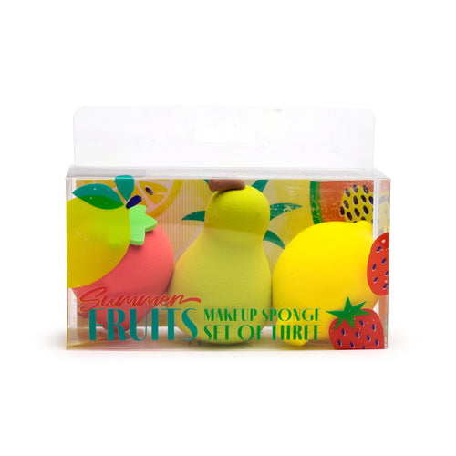 Front view of a 'Summer Fruits Makeup Sponge Set of Three' in clear plastic packaging. The set contains a pink rounded sponge, a light green pear-shaped sponge, and a yellow lemon-shaped sponge, against a colourful fruit-patterned background.