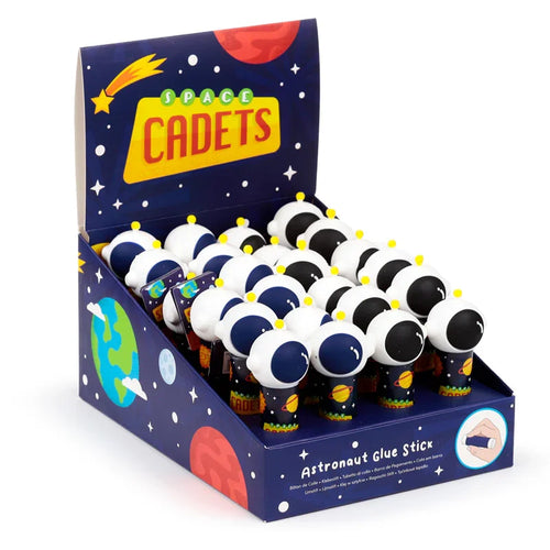 Angled view of a dark blue display box, decorated with a space theme and 'SPACE CADETS' lettering, filled with numerous astronaut-themed glue sticks. Each glue stick features a white helmet with a dark visor and yellow antenna, over a dark body with planet illustrations.