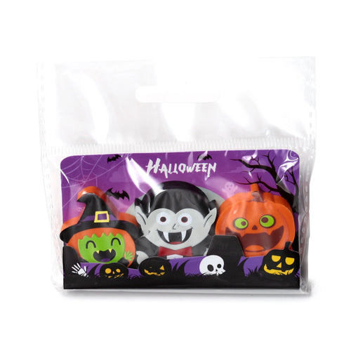 Front view of a three-piece Halloween erasers set in clear plastic packaging, depicting a green-faced witch, a white-faced vampire, and an orange pumpkin on a purple backing card.