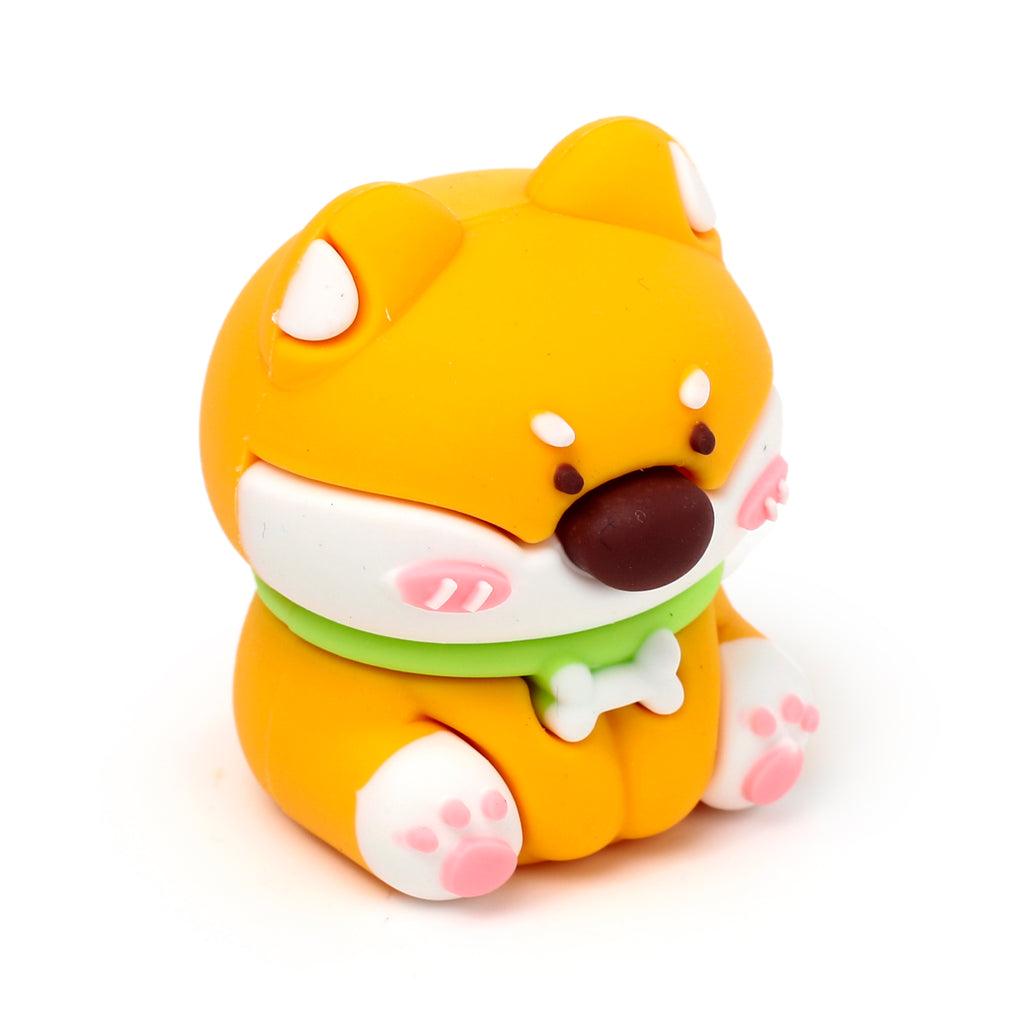 Angled view of an orange and white Shiba Inu dog 2-in-1 sharpener and eraser, featuring a dark brown nose, pink cheeks and paw pads, wearing a light green collar with a white bone detail.