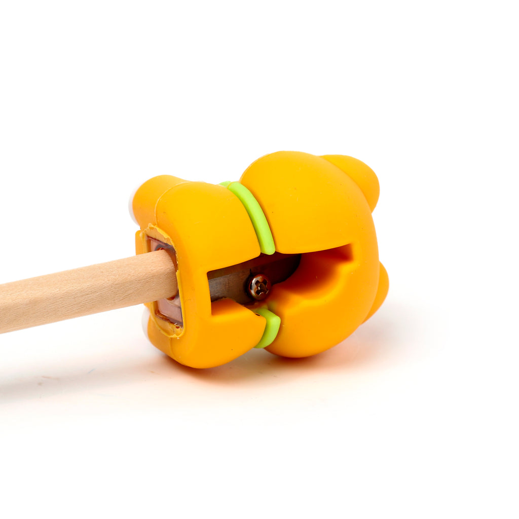 Angled close-up of an orange Shiba Inu-shaped 2-in-1 pencil sharpener and eraser with a green band, actively sharpening a wooden pencil.