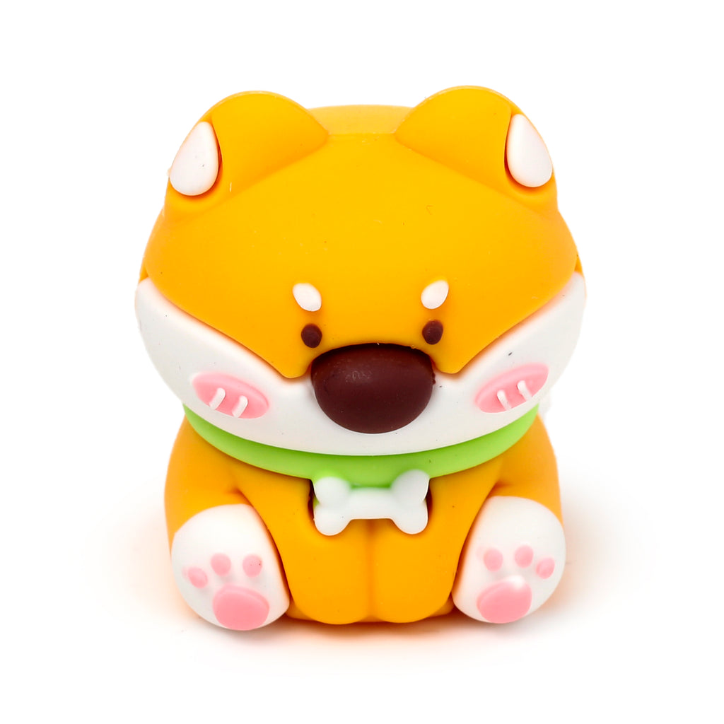 Front view of a cartoon-style orange and white Shiba Inu dog pencil sharpener and eraser, featuring a green collar with a bone tag and pink paw pads.