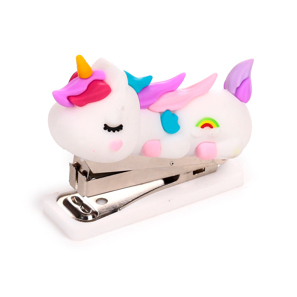 Angled view of a white unicorn mini stapler, featuring a yellow horn, pink mane, blue and pink wings, and a rainbow motif, with a silver stapling mechanism on a white base.