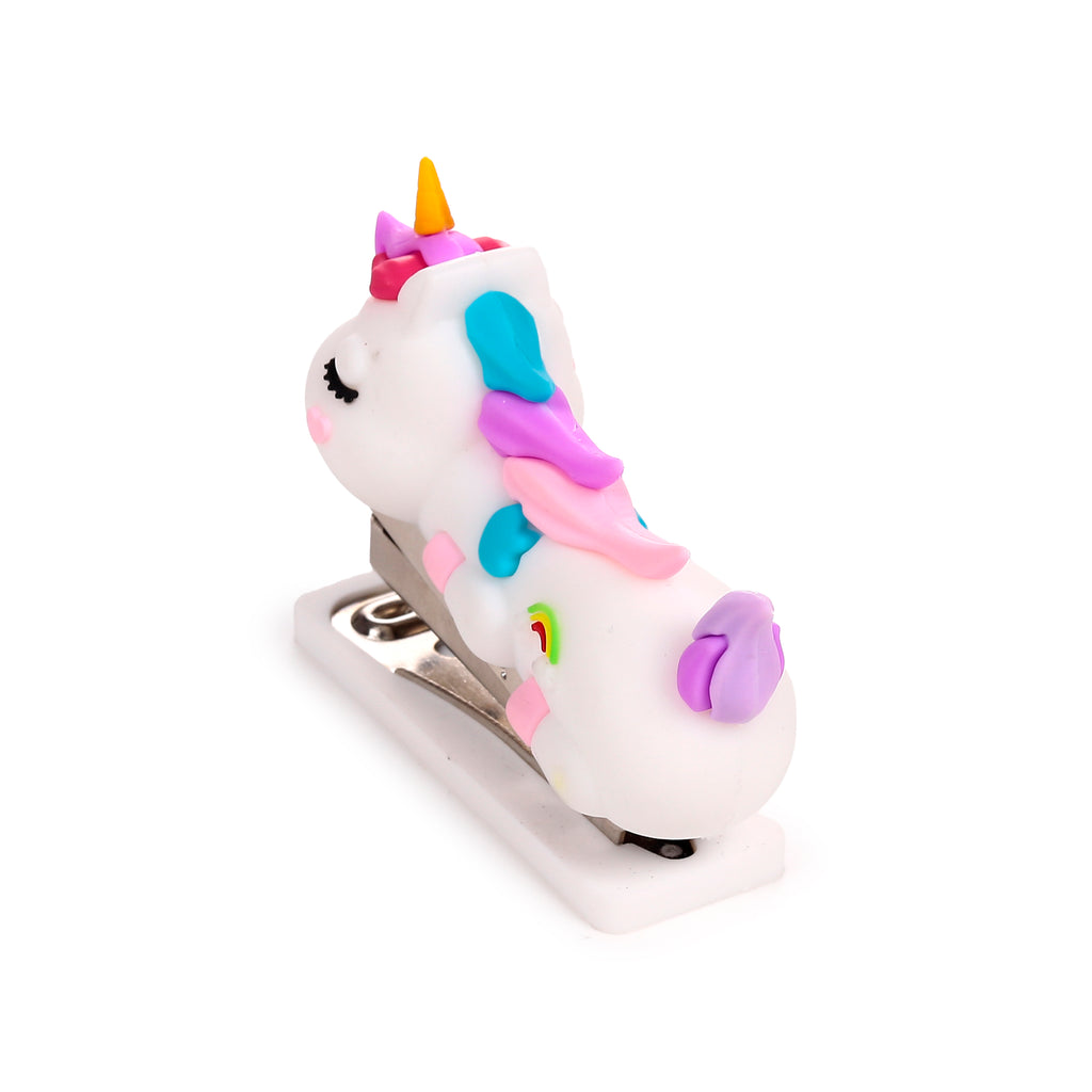 Angled view of a white mini unicorn stapler, showing its closed eyes, pink cheeks, yellow horn, pink, purple, and blue mane, and a small rainbow design on its side.