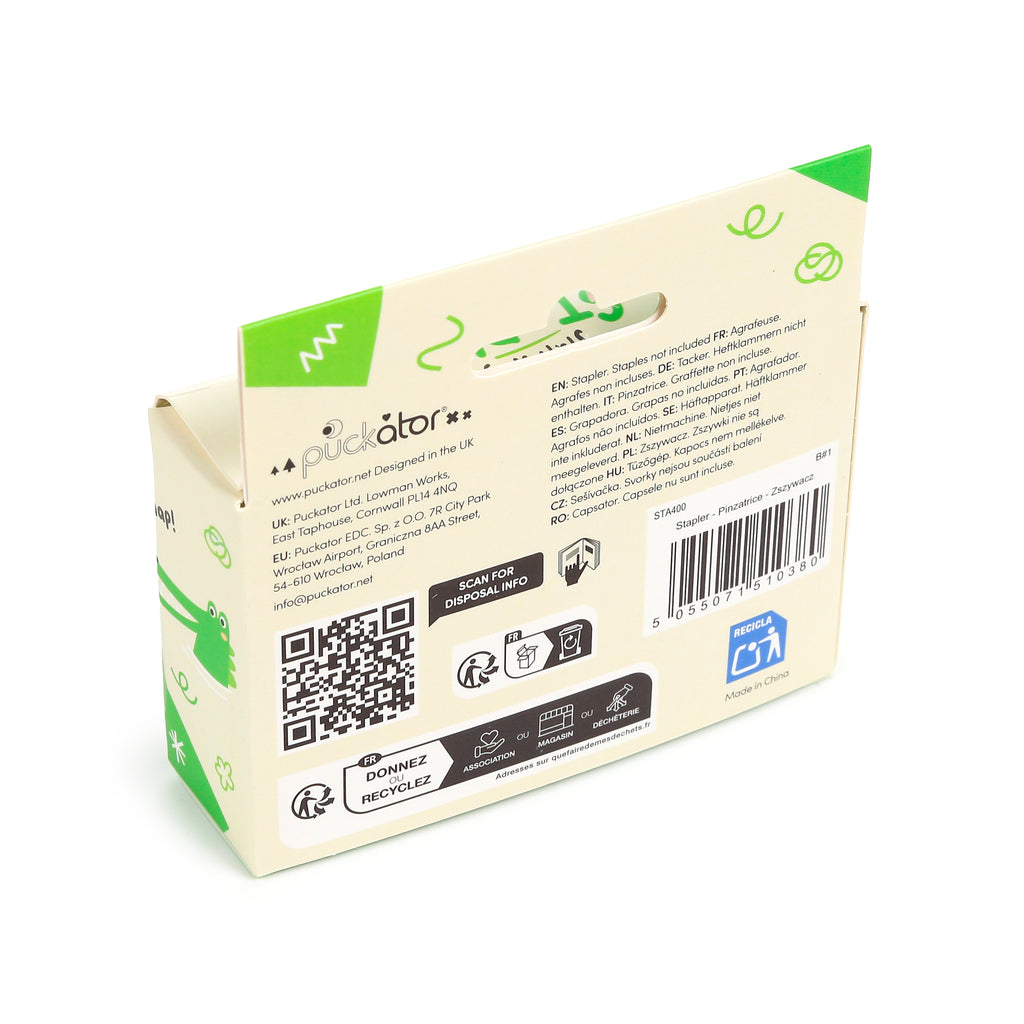 Angled rear view of packaging for a mini crocodile stapler, showing a barcode, QR code, recycling symbols, and multilingual text indicating staples are not included, set against a pale cream background with green accents.